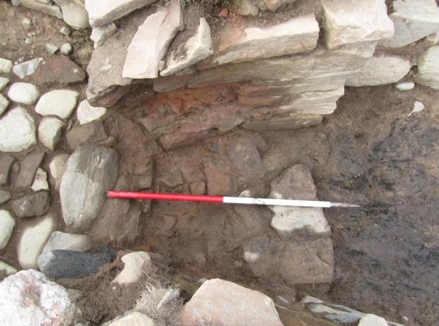 The flue, post excavation, from the east with the reddened and fire cracked paved hearth and walls - note also the “tipping” stone feature to the left